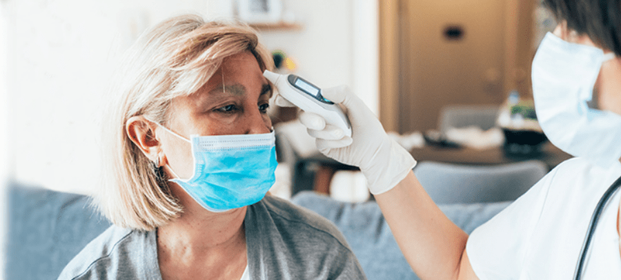 woman with blue mask getting her temperature read