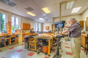 Man standing at saw cutting wood in workshop